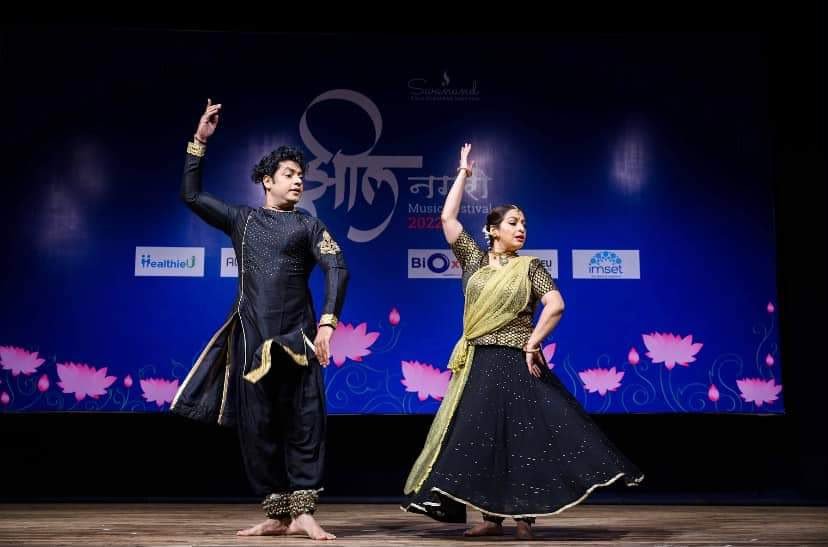 Two Kathak dancers performing on stage in classical costume