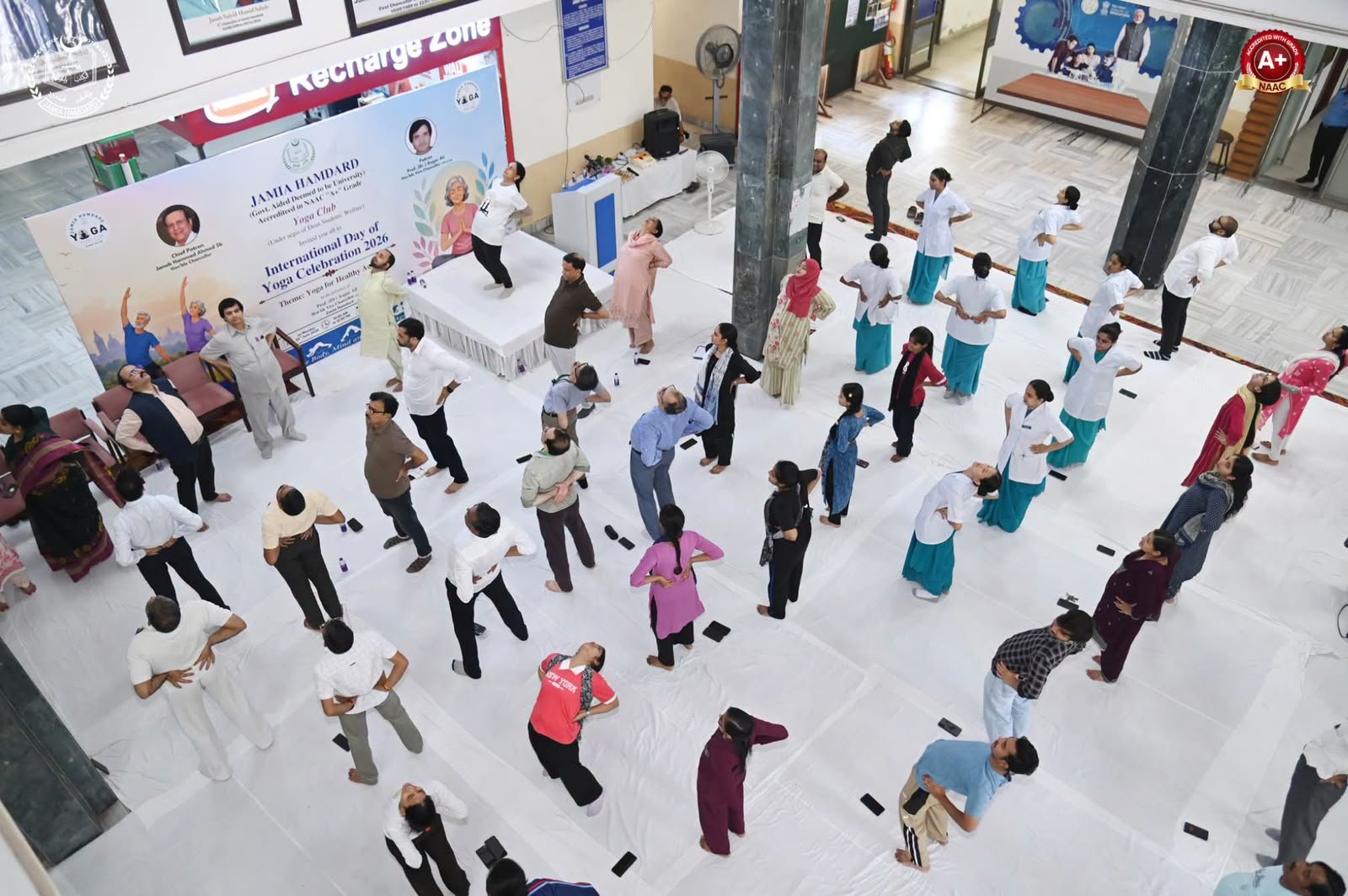 Large corporate yoga session with staff practising together in an office hall