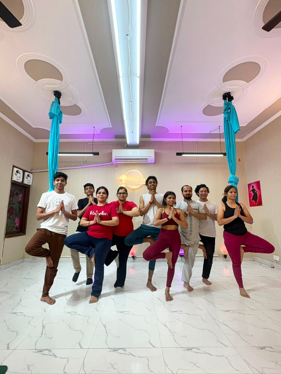 Group yoga class holding tree pose at the Yoga24Fitness studio in Vasant Kunj